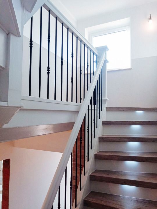 Landhausstil, elegant und edel: Kontraste, zierliche Metallstäbe und individuell gefertigte Säulen zeichnen diese Treppe aus. Alles gefertigt nach Kundenwunsch.